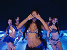 a woman in a bikini is covering her eyes while dancing with other women .
