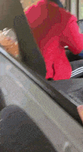 a person in a red sweater is walking on a treadmill