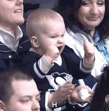 a baby wearing a penguins jersey holds up his fist in the air