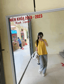 a girl taking a selfie in front of a mirror that says nien khoa 2019 2023