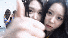 two girls are posing for a picture and one of them is giving a thumbs up .