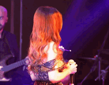 a woman with long red hair is singing into a microphone on stage