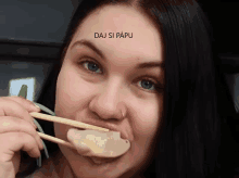 a woman is eating something with chopsticks and the words " daj si papu " above her face