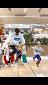 a group of people are dancing in a mall and one of them is jumping in the air .