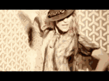 a woman wearing a hat is dancing in front of a wall with a pattern .