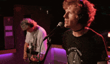 a man singing into a microphone while another man plays guitar