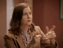 a woman in a suit is clapping her hands in a room