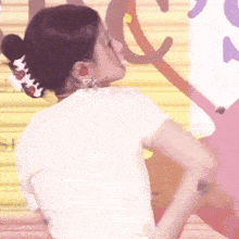a woman wearing a white shirt and earrings is standing in front of a colorful background .