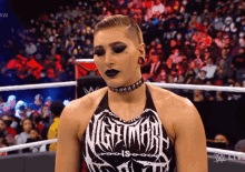 a woman is standing in a wrestling ring wearing a choker and a shirt that says nightmar .
