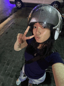a girl wearing a helmet giving the peace sign