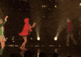 a group of people are dancing on a stage in front of a purple light