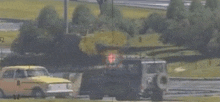 a yellow car with the number 8 on the side is driving down a road next to a truck .