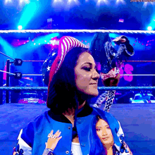 a woman in a wrestling ring is wearing a blue jacket with the word left on it