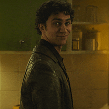 a man with curly hair wearing a black leather jacket is smiling