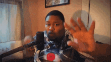 a man in a camo shirt is talking into a microphone and making a funny face