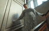 a woman in a sequined dress and white gloves is walking down a set of stairs
