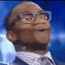 a close up of a man wearing glasses and a suit with the word nope written below him