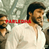 a man in a white shirt stands in front of a sign that says parledha