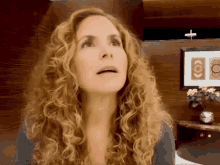 a woman with curly hair is looking up at something