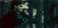 harry potter is standing in front of a tree in a dark room .