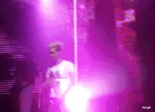 a man in a white shirt is standing in front of a purple light .