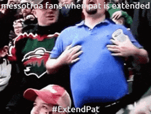 a man in a blue shirt holds his hands to his chest in a crowd of people ..