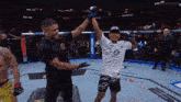 a referee holds up a fighter 's arm in a ufc ring