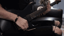 a man is playing a black electric guitar with the letter g on it