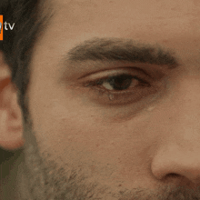 a close up of a man 's eye with a tear coming out of his eye