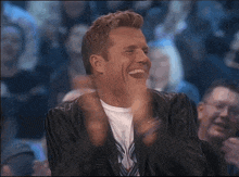 a man in a suit is laughing and clapping