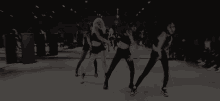 a group of women are dancing in front of a mirror in a dark room .