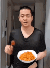 a man in a black shirt is holding a plate of food