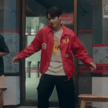 a man wearing a red jacket and black pants is dancing in a room .