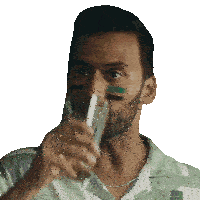 a man with green and black paint on his face is drinking from a glass
