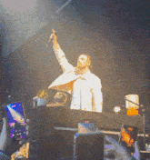 a man singing into a microphone while a crowd takes pictures