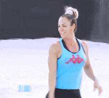 a woman in a blue kappa tank top smiles