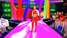 a female wrestler is walking down a pink carpet while holding a sign that says free hugs
