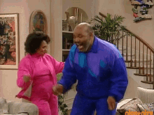 a man in a blue jacket is dancing with a woman in a pink outfit .