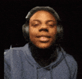 a man wearing headphones and a blue hoodie is smiling