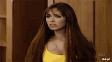 a woman with long hair and a yellow tank top is making a funny face .