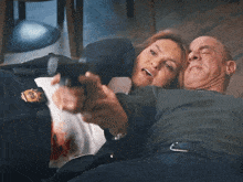 a man is pointing a gun at a woman laying on the ground