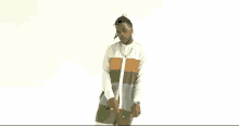a man with dreadlocks is standing in front of a white background wearing a striped shirt and shorts .