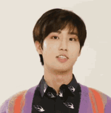 a young man wearing a black shirt and a purple cardigan