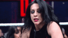 a woman in a black dress is standing in a wrestling ring with her mouth open .