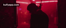 a man in a suit is holding a gun in a red room .