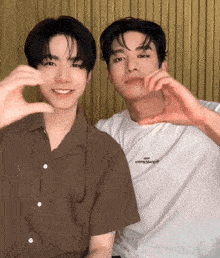 two young men are making a heart shape with their hands and one of them is wearing a shirt that says " happy margiel "