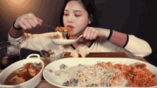 a woman is eating a spoonful of food from a white plate