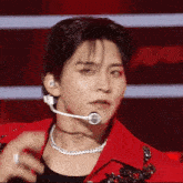 a close up of a man wearing a red jacket and a necklace with a microphone on his neck .