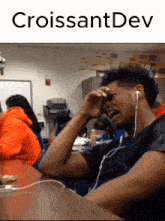 a man wearing headphones is crying in front of a sign that says " croissantdev "