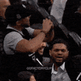 a man in a black hat is taking a picture of another man in a crowd of people .